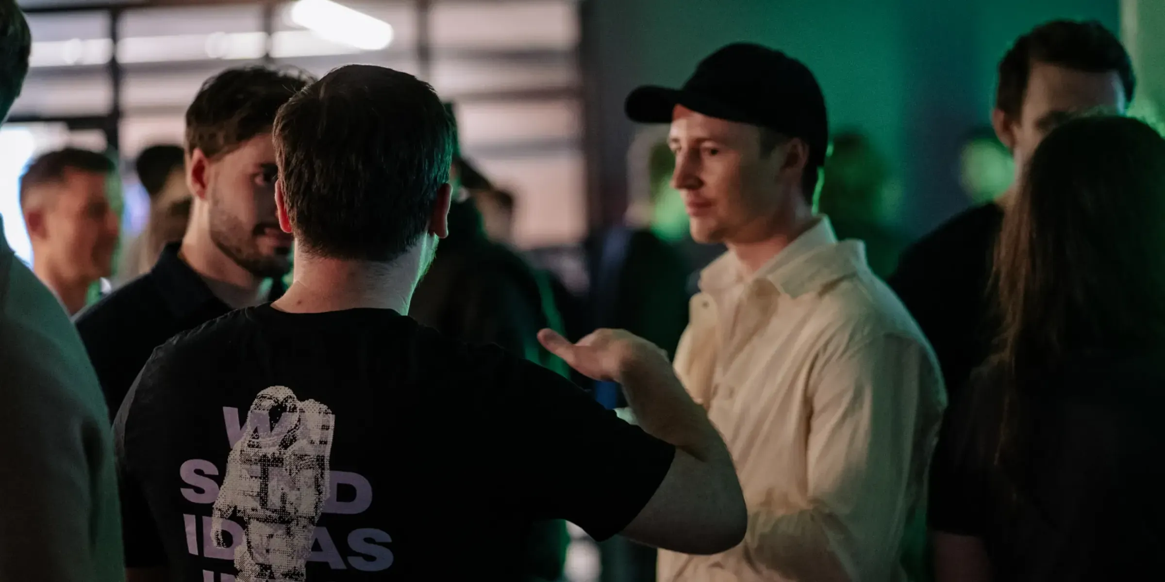 Kollegor och gäster minglar i Weapps lokal under ett kvällsevent, i grönt scenljus